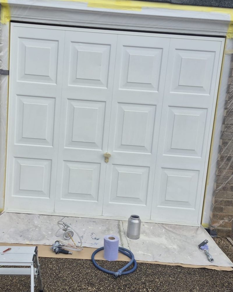 Garage door before spraying, masked off and white