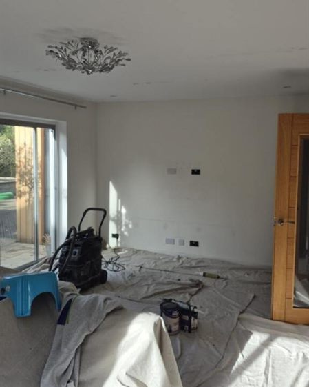 Living room patio-door wall before painting, with the room under dust sheets